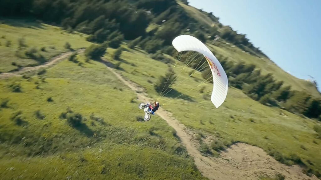 Un pilote Red Bull Dirt Biker saute d'une falaise et fait du parapente jusqu'en bas